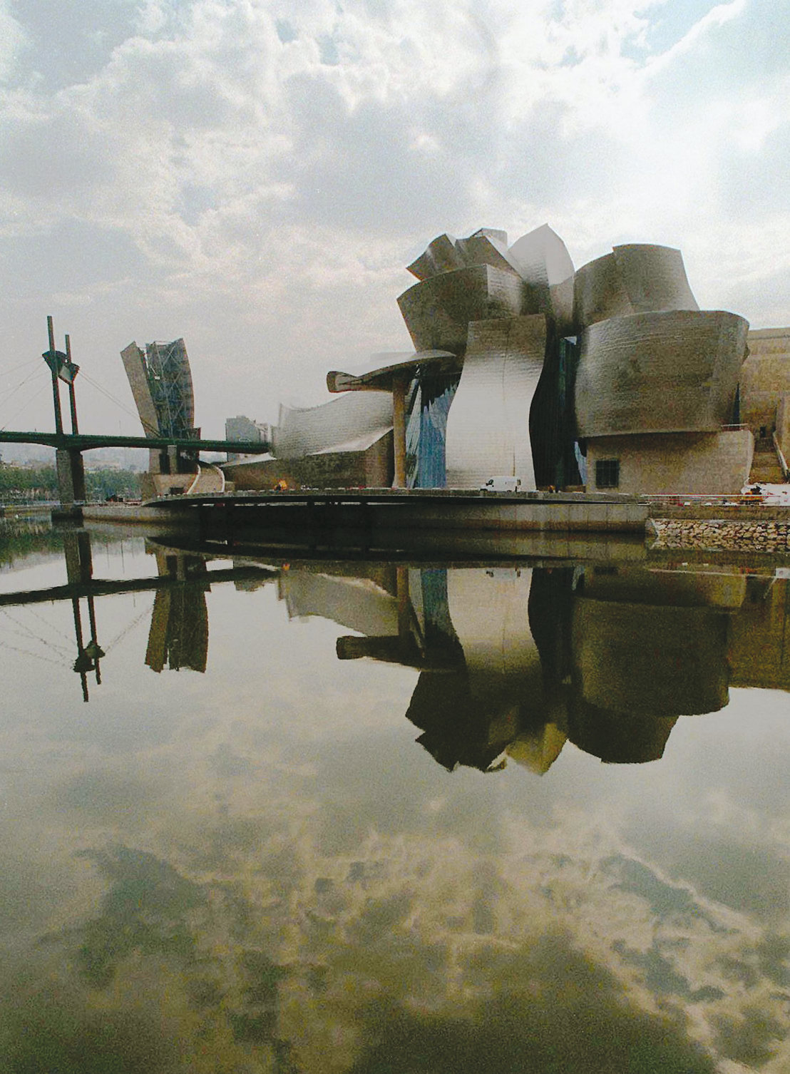 Photograph of exterior building made up of cylindrical and ribbon shapes next to body of water. 