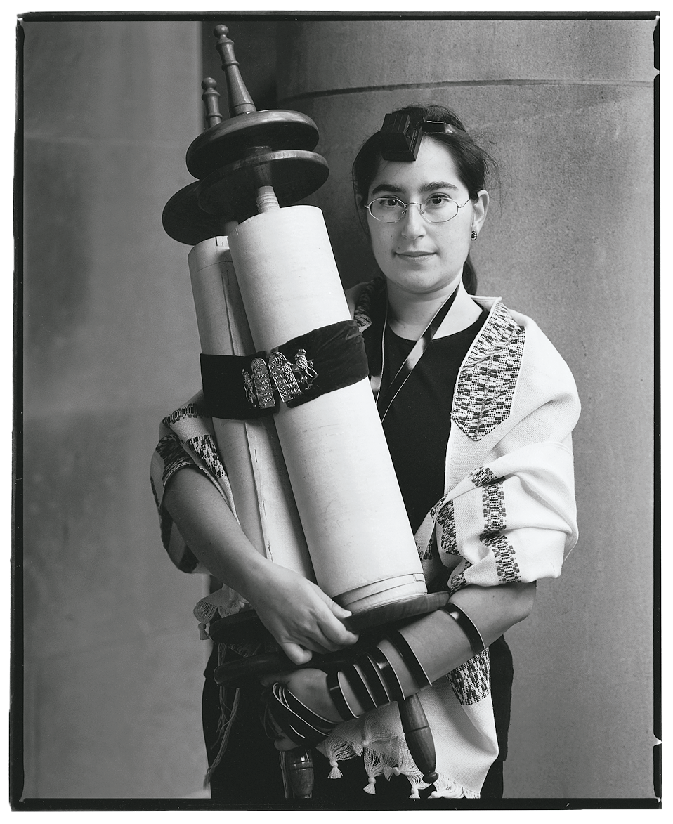 Full body photograph of a person in glasses holding scroll with left arm wrapped in leather strap. Full body photograph of a person in glasses holding scroll with left arm wrapped in leather strap.