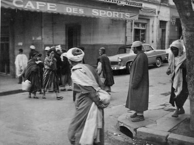 Black and white photo of street with people and store awning.