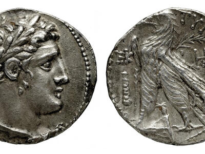 Ancient silver coin showing a laurel-wreathed profile on one side and an eagle standing on a thunderbolt with Greek inscriptions on the other side.