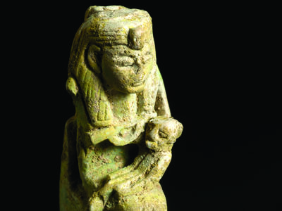 Faience amulet with Egyptian goddess wearing headdress sitting on a throne and holding a child.