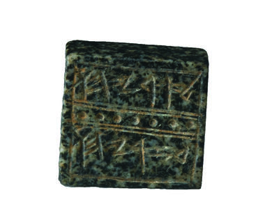 Square rock seal decorated with lines and dots that surround a Hebrew inscription.