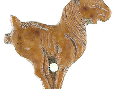 Ivory sculpture of goat with feet close together and hole in center.