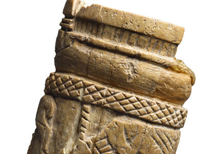 Ivory handle with carving of two grazing deer-like animals, herringbone motif, and a series of circles.