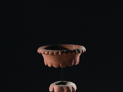 Ceramic chalice with tall, hollow stand and bowl in a separate piece on top and secured to bottom of chalice with a rod.