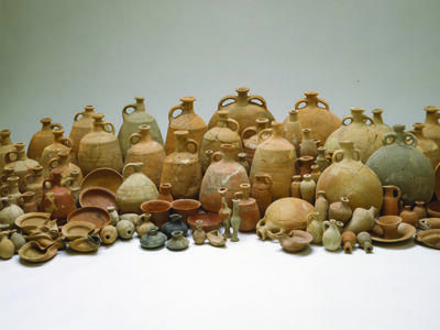 Collection of many ceramic containers including bowls, bottles, decanters, jugs, and oil lamps.