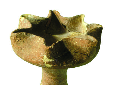 Ceramic oil lamp with seven spouts on a pedestal.