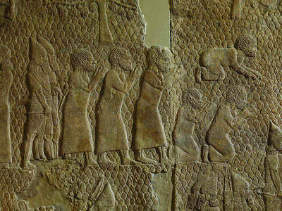 Wall relief showing six men dressed in tunics, one prostrate and two kneeling, with two bearded soldiers behind them.