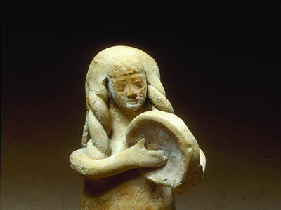 Terra-cotta figurine of women with long hair playing frame drum. 