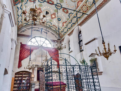 Photograph of room with decorated ceiling, central platform with wrought-iron gate, and bookshelf on far wall.