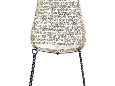 Plaque with Hebrew text and two chains hanging from the bottom.