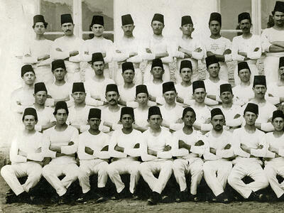 Group portrait of men dressed alike and wearing fezzes.
