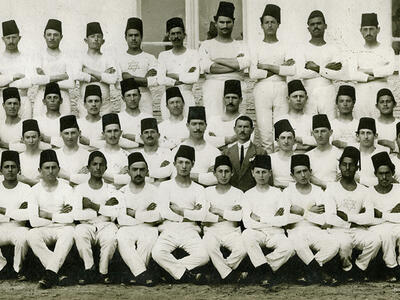 Group portrait of men dressed alike and wearing fezzes.