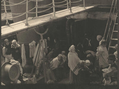 Photograph of a ship deck with two stories filled with people.