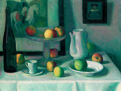 Painting of table with plates, fruit, and bottle with small painting of man on horse in the background.