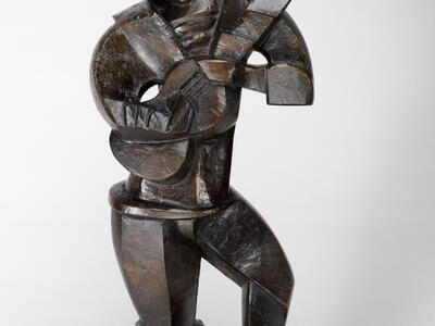 Sculpture of abstract figure standing and holding a guitar.