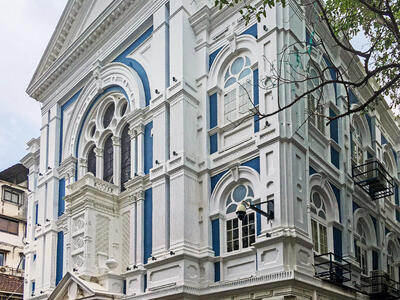 Photograph of building façade with significant decorative trim on window frames and beams.