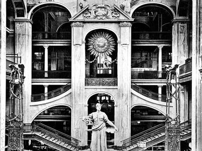Photograph depicting tall statue in the center of large atrium with interior staircases.