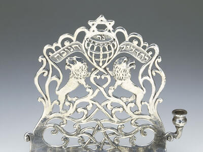 Eight-branched candelabrum with backplate with lions, a Hebrew inscription, Stars of David, and a scalloped top edge. 