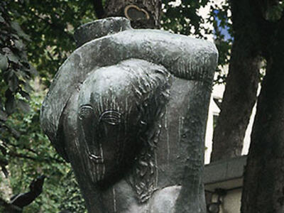 Sculpture of stylized nude woman carrying water over her head.