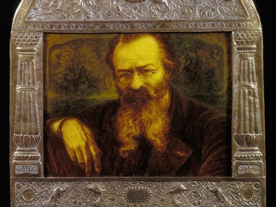 Painting of man in beard and glasses set inside an ornate frame with decorated border. 