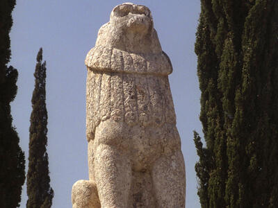 Statue of a lion roaring toward the sky on pedestal with Hebrew writing.
