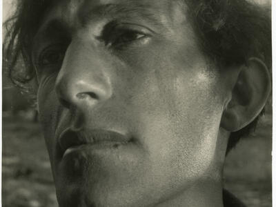 Close-up photograph of man's face. He has no expression and is looking to his right.