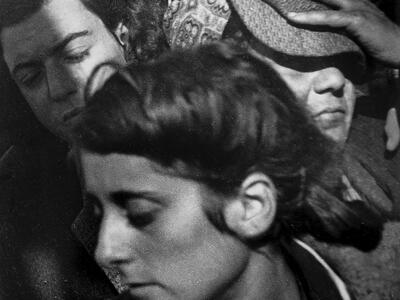 Photograph of female immigrants crowded together, with their faces turned away from viewer.