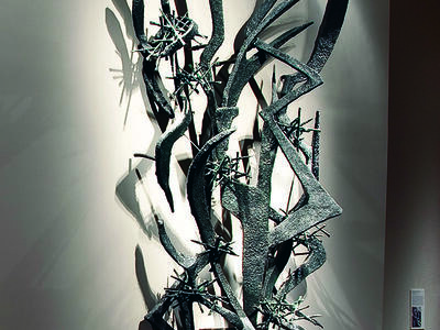 Large-scale abstract sculpture of sharp metal lines and edges installed on wall.