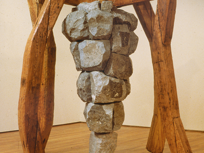 Sculpture of iron grape cluster hanging on wooden framework.
