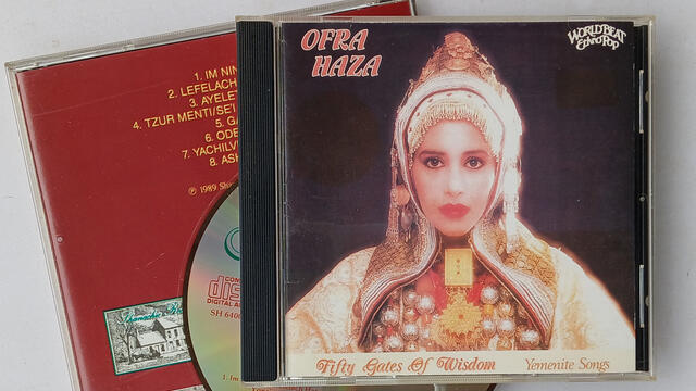 Front and back of CD case with CD. The front has a picture of a woman in Yemenite dress, with the words "Ofra Haza" on the top left, and "Fifty Gates of Wisdom" and "Yemenite Songs" on the bottom.