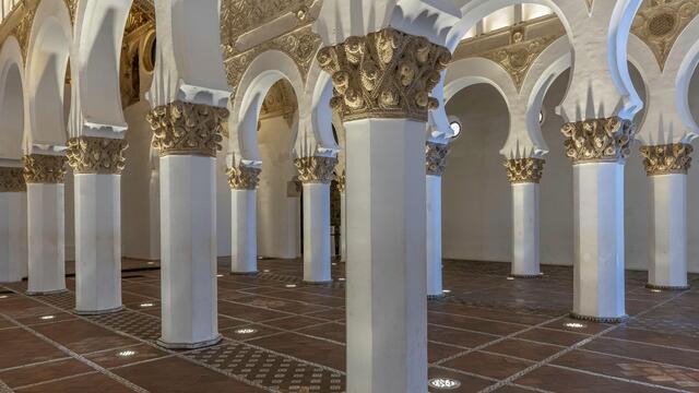 Photo of a large room with several octagonal white columns with gold decorative features.