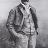 Photograph of man standing with hands in his pockets.