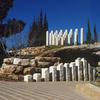 Monument featuring several stelae of different heights set along a rocky cave. 